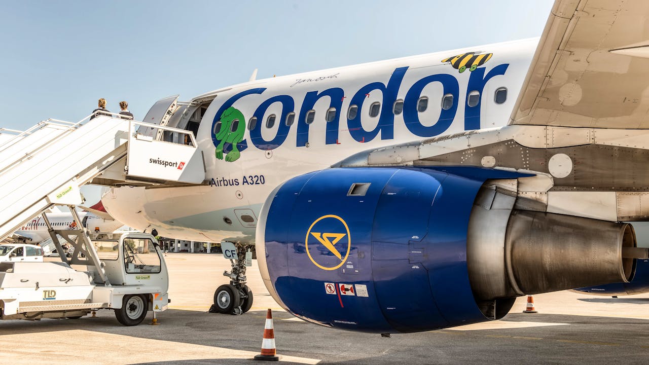 Airbus A320 aircraft at Kos Airport with passenger boarding via Swissport stairs.