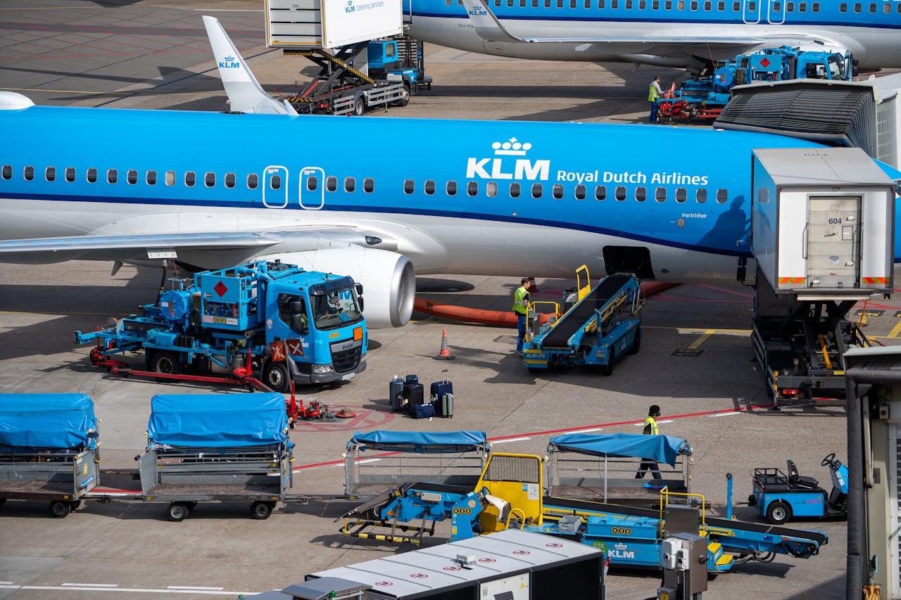 KLM airplane at airport being serviced by ground crew and equipment for departure.